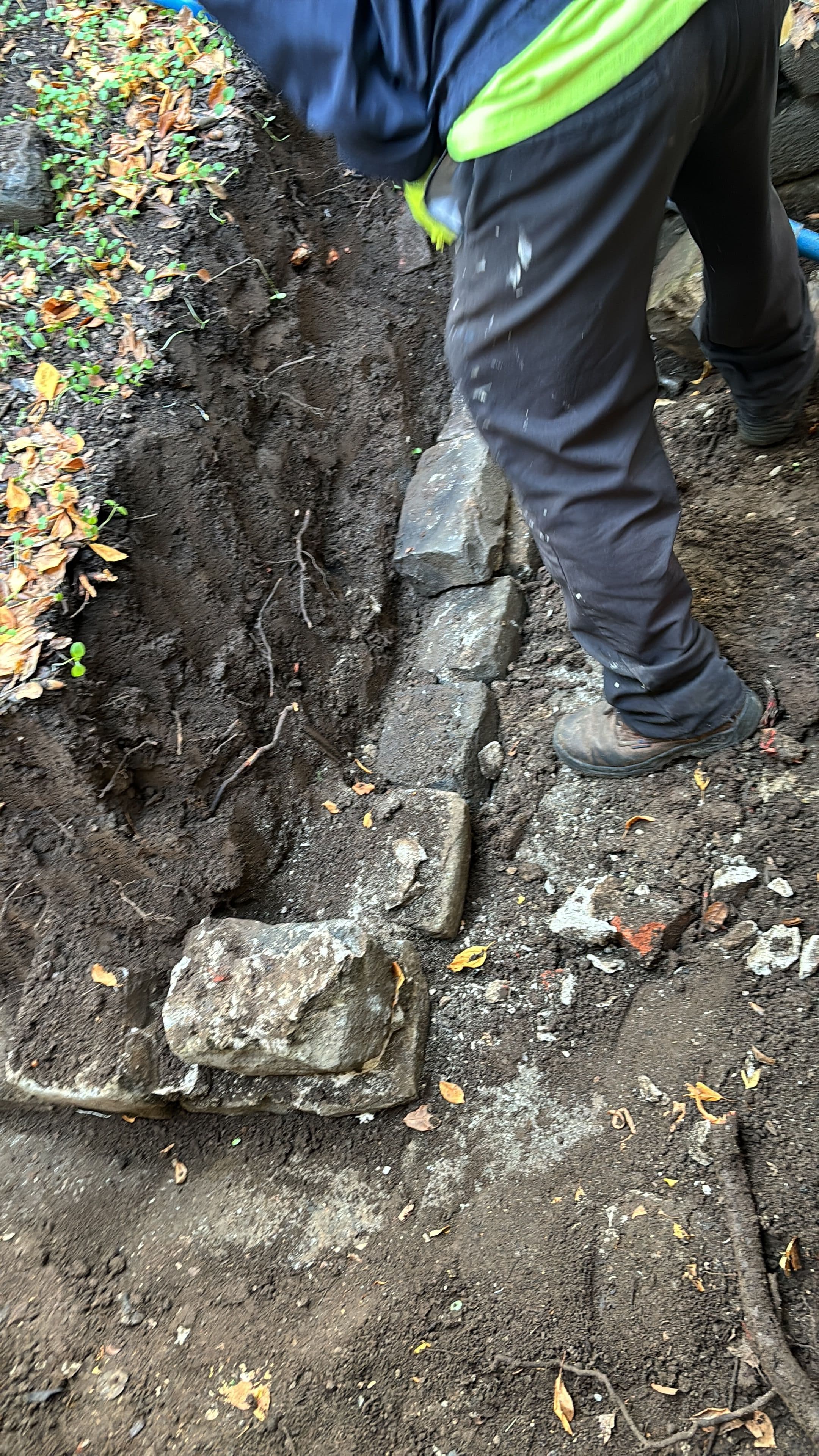 Person laying stones in a trench for landscaping or construction project.